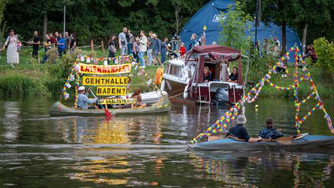 Bootskorso beim Laternenfest in Halle (Saale) 2023: bunt geschmückte Boote auf der Saale, Banner „Geht Halle baden?“ und Zuschauer am Ufer