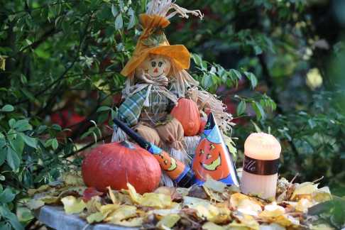 Herbstdekoration mit Kürbissen, Vogelscheuche und buntem Laub